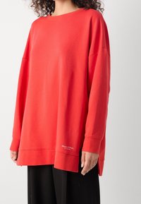 Rood oversized sweatshirt van zachte katoen, met lange mouwen, een brede halslijn en een klein logootje aan de onderkant.