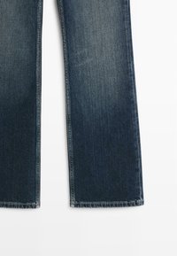 Jeans blu scuro con design a gamba dritta, realizzati in denim, con un colore uniforme e una minima scoloritura sulle ginocchia. I bordi sono cuciti.