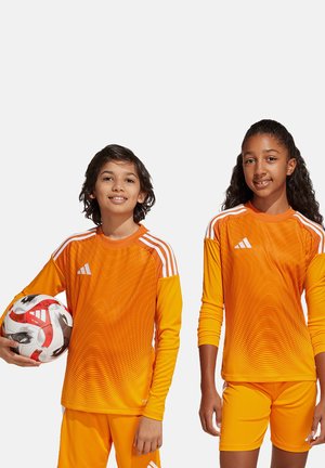 Uniformes de football orange vif avec un motif texturé, comportant des manches longues et un short, accompagnés d'un ballon de football, accentués par des rayures blanches.