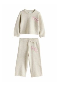 Cream-colored knit sweatshirt and matching pants, featuring "NYC" embroidered in pink. Relaxed fit with ribbed cuffs and waistband.