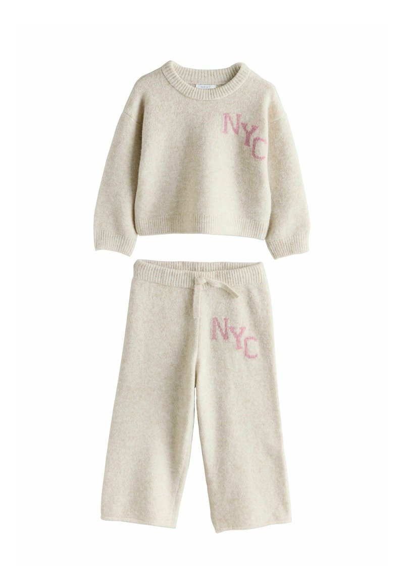 Cream-colored knit sweatshirt and matching pants, featuring "NYC" embroidered in pink. Relaxed fit with ribbed cuffs and waistband.