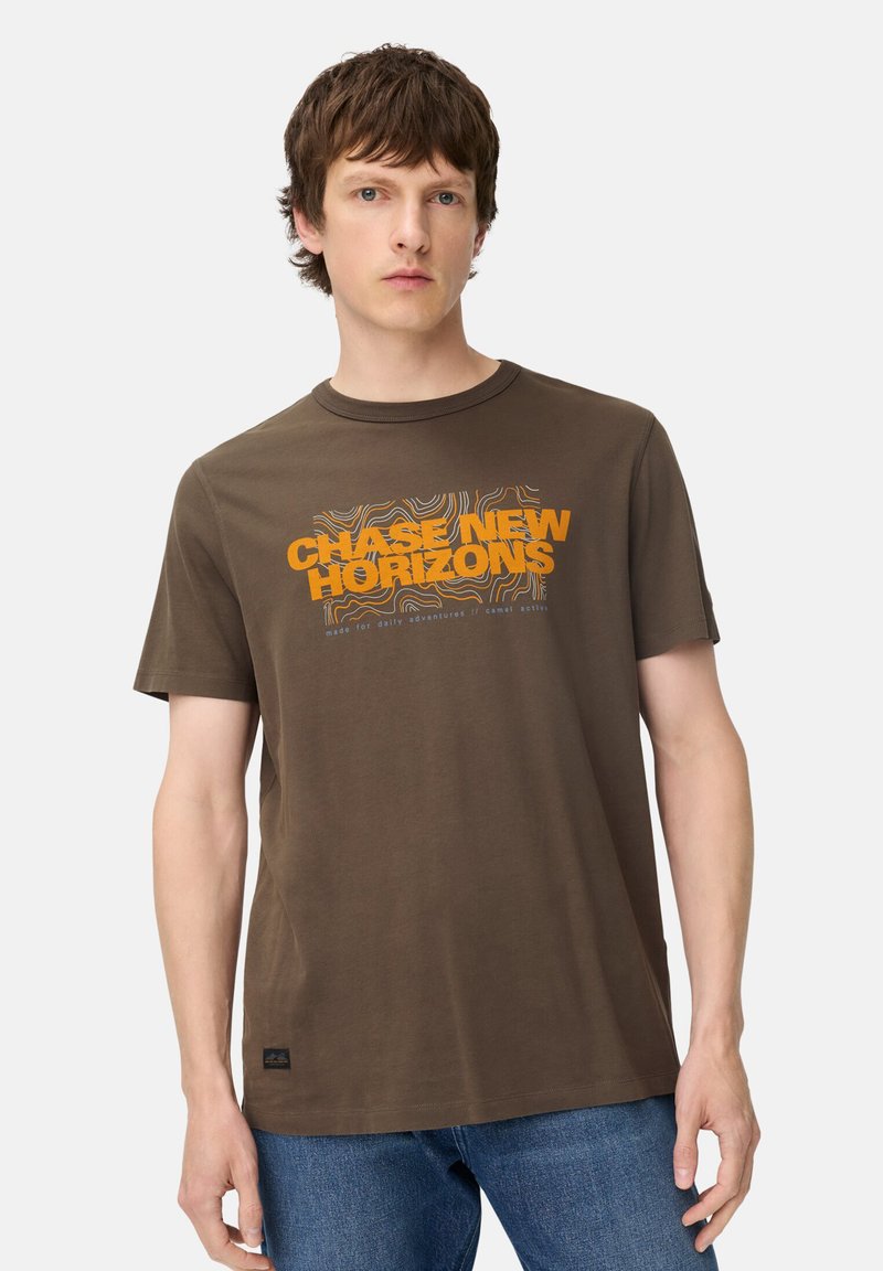 Brun kortærmet t-shirt lavet af bomuld, med en orange grafisk tekst "CHASE NEW HORIZONS" og bølgende linjemønstre på fronten.