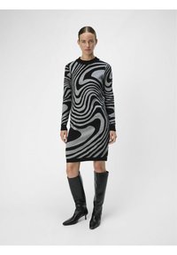 SüNNIKS KLEIT, millel on musta ja halli swirl-muster, pikad varrukad, erilised ribatud kaelused ja keha lähedane siluett, mis ulatub kuni keskmise reieni.