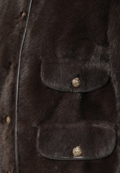Brun pelsjakke med en myk tekstur, runde gullknapper, lærdetaljer og to frontlommer med klaffelukking.