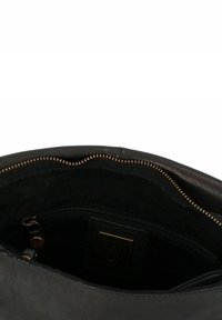 Interno di una borsa nera in pelle con una texture morbida, dotata di una tasca con zip e dettagli della zip in tono oro lungo l'apertura.