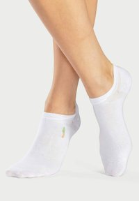 Calze alla caviglia bianche in misto cotone. Presentano un piccolo disegno ricamato di ananas sul lato esterno. Texture liscia e forma aderente.