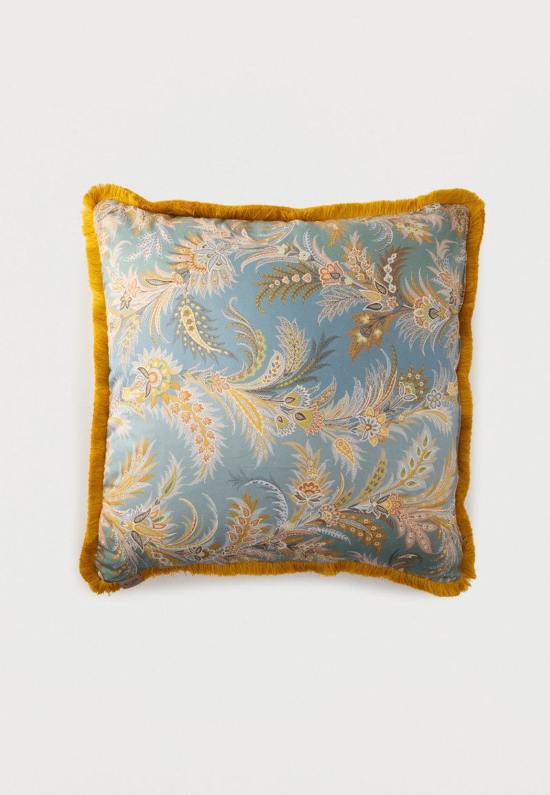 Coussin carré avec fond bleu, motifs floraux paisley complexes en or et beige, avec bordure à franges jaune moutarde.