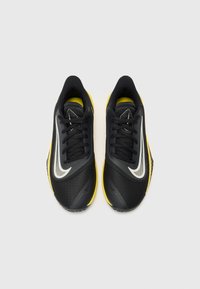 Black athletic sneakers with yellow soles, featuring a textured upper, black laces, and a reflective white swoosh design on the sides.