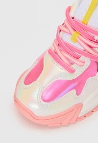 Chunky sneaker med iriserende hvite og rosa paneler, sterke rosa snørebånd, en gul snørebåndsløkke og en teksturert rosa såle.