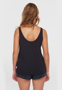 Zwart mouwloos shirt met wijde armsgaten en een afgeronde achterkant van de halslijn, gemaakt van een soepele, lichte stof. Gepaard met opgerolde denimshorts.