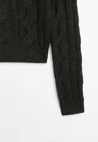 Pull gris foncé en maille torsadée avec une coupe courte et des détails côtelés sur l'ourlet et les poignets. Présente des motifs texturés sur toute la surface.