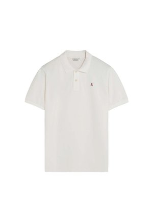 Polo blanco de manga corta con cuello, dos botones y pequeño logo rojo de calavera en el pecho izquierdo.
