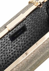 Silver metallic clutch bag with a textured exterior, gold-tone hardware, and a dark patterned interior featuring a brand label.