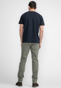 Camiseta navy de manga corta combinada con pantalones verde claro. Camiseta de algodón, pantalones de una tela suave con bolsillos traseros y zapatos marrones.