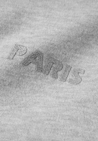 Grey fabric with a textured surface featuring the word "PARIS" in shiny, embossed silver letters. The design is simple and minimalist.