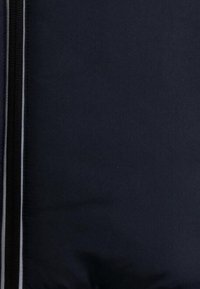 Schwarze gepolsterte Jacke mit glatter Textur, ausgestattet mit einem Reißverschluss an der Vorderseite und reflektierenden Akzenten entlang der Nähte. Das Material wirkt robust und wasserabweisend.