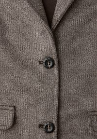 Brązowa teksturowana kurtka z klapowym kołnierzem, dwoma przednimi kieszeniami oraz czarnymi guzikami z grawerowanym wzorem.