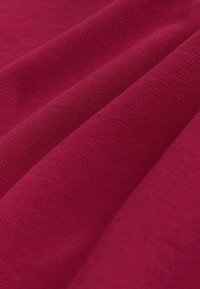 Bordeaux katoenen stof met een gestructureerd oppervlak, dat plooien en kreuken toont die de zachtheid en diepte benadrukken.