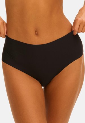Woman wearing black high-waist seamless underwear, holding sides of waistband against a plain light background.