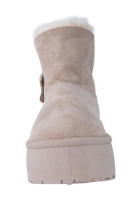 Botín de ante beige con una superficie texturizada, puño acolchado y suela de goma gruesa con un ligero elevación. Forro suave visible en la parte superior.