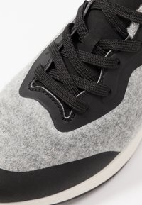 Dessus gris en feutre avec des accents et des lacets en synthétique noir. Bout rond et conception de semelle rembourrée. Surface texturée pour une meilleure adhérence.