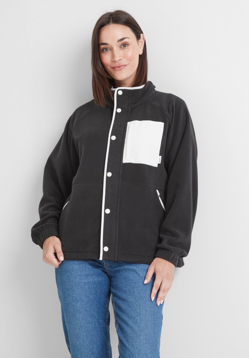 Black fleece jacket with a white chest pocket, white piping along the front, and side zip pockets. Features a high collar and elastic cuffs.