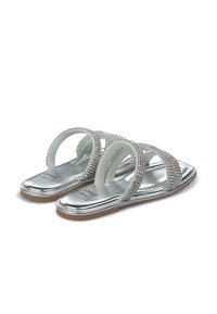 Sandali piatti argento con tre cinturini decorati con strass, una soletta metallica lucida e una suola in gomma marrone chiaro.