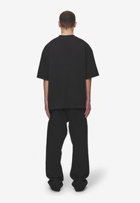 Černé oversized tričko a tepláky, bavlněná tkanina, volný střih, kulatý výstřih, spadlého ramena, minimalistischek design, bez viditelných vzorů nebo akcentů.