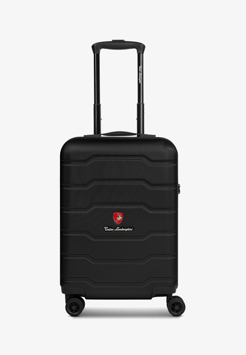 Valise noire à coque dure avec texture striée, poignée rétractable, quatre roues et un logo à l'avant. Design compact et robuste.
