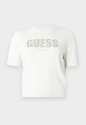 Maglione bianco a maniche corte in materiale lavorato a maglia con il logo "GUESS" in argento e la scritta "EST. 1981" sotto. Tessuto liscio e design aderente.