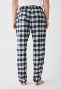 Šedé a námornícke kockované pyžamové nohavice s elastickým pásom, s jednou zadnou vreckom a voľným strihom. Mäkká flanelová textúra.
