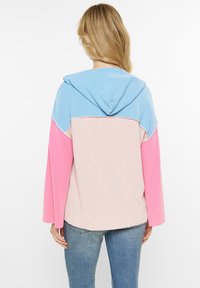 Kapuzenpullover aus blauer, rosa und beiger gerippter Stoff; verfügt über einen lässigen Schnitt, lange Ärmel und ein strukturiertes Muster.