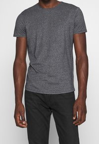 Grijze t-shirt met korte mouwen, gemaakt van een zachte, textuurstof, met een minimalistisch logo op de borst en een klassieke ronde hals.