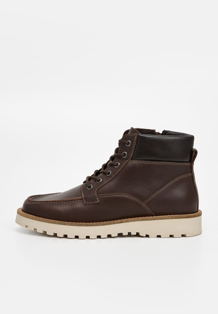 Braune Leder-Ankle-Boots mit einer glatten Textur, cremefarbener Gummisohle, Schnürung vorne und gepolstertem Kragen für zusätzlichen Komfort.