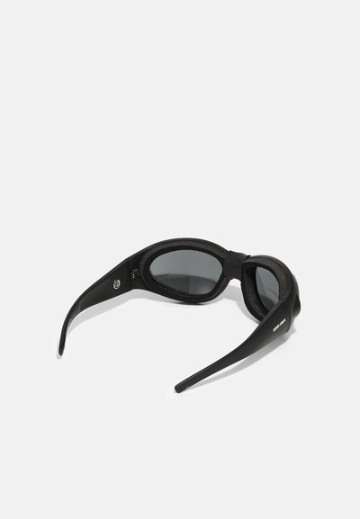 Gafas de sol negras con un diseño elegante y curvado. Presentan bordes acolchados, lentes oscuros y patillas largas y robustas.