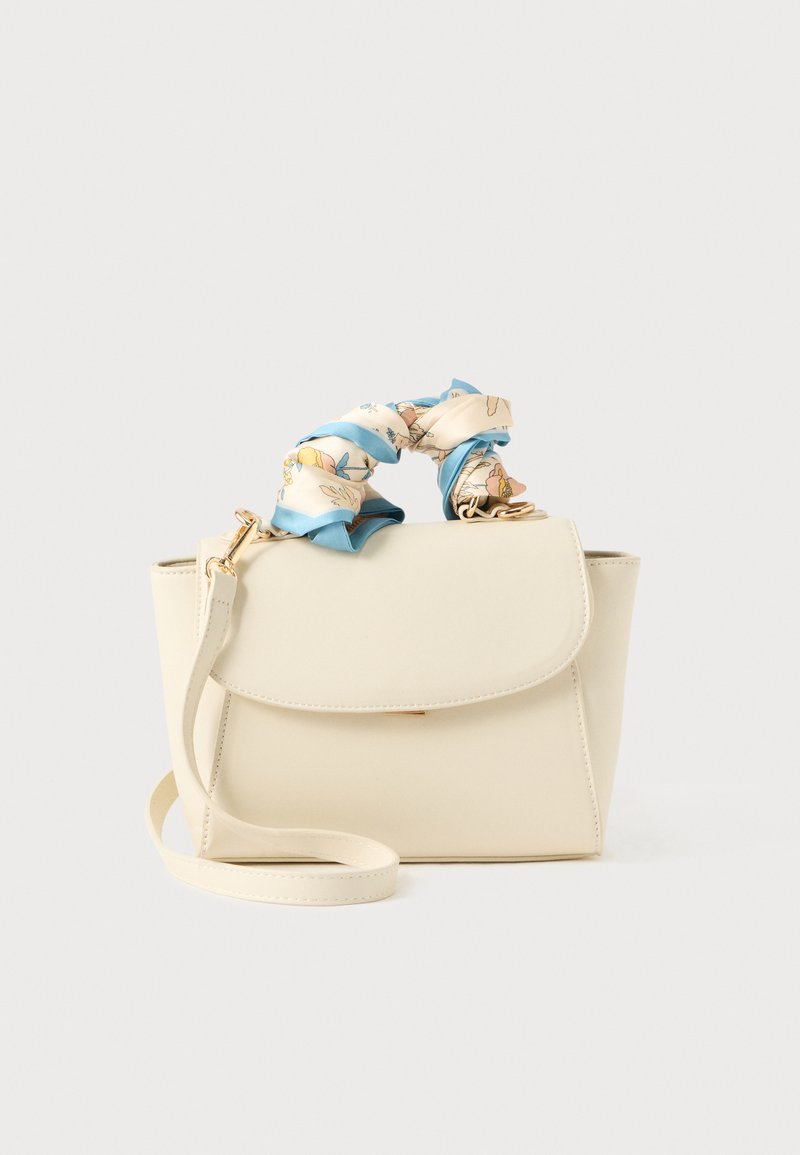 Sac à main couleur crème avec une anse enveloppée d'un tissu à motifs floraux bleu et beige, et une bandoulière réglable sur fond blanc.