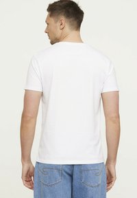 Witte kotoen t-shirt met korte mouwen, voorzien van een ronde hals, een eenvoudig ontwerp en een relaxte pasvorm, gedragen met blauwe denim jeans.