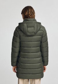 Dunjacka i mörkgrön med huva. Föreslå horisontell sömnad, en midjelång design och en slät yta.