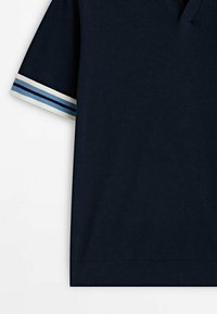 Pull-over en bleu marine à manches courtes avec un col en V et des poignets côtelés rayés en blanc, bleu clair et bleu marine au niveau des manches et de l'ourlet.