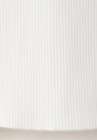 Gros plan sur une texture de tissu blanc côtelé avec des lignes verticales et un motif tricoté doux et légèrement en relief.