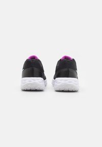 Baskets de sport noires avec une tige en maille texturée, semelle blanche et accents roses au talon. Présente un design de bout lisse et arrondi.