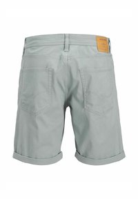 Ljusgröna denimshorts har en vikt nederkant, två bakfickor och en brun läderlapp på midjan med varumärkesinformation.