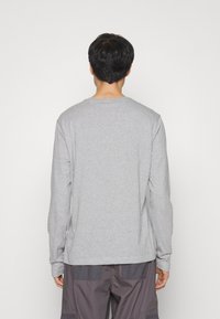 Grijze longsleeve shirt van zachte stof, met een ronde hals en een slanke pasvorm, afgewerkt met geribde manchetten en een rechte onderkant.
