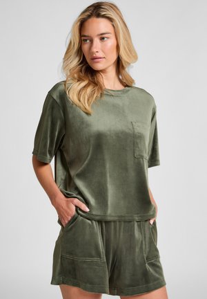 Olijfgroene lounge-outfit gemaakt van zachte, gestructureerde stof. Bevat een top met korte mouwen en een zak, en bijpassende shorts met voorzakken.