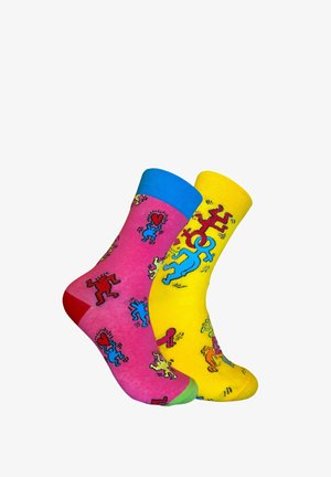 Calcetines de algodón coloridos: uno rosa con acentos rojos y azules, y otro amarillo con patrones azules, que presentan figuras de dibujos animados juguetonas.