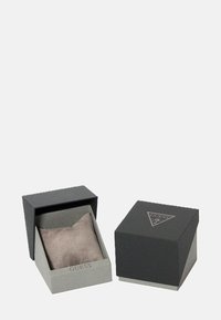 Musta ruudukujuline kinkekarp halli sisuga. Pehme, plüüsist polster keskmes. "GUESS" on esiküljel reljeefselt toodud. Kaane avatud disain.