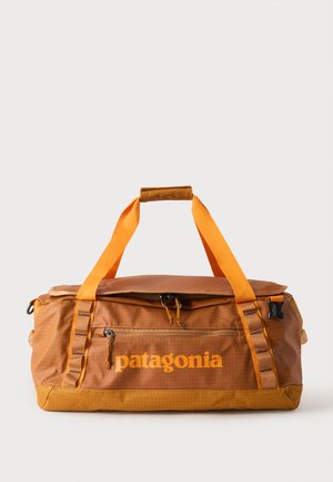 Sac polochon Patagonia marron et orange avec poche avant zippée et deux poignées de transport sur un fond clair uni.