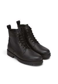 Czarne skórzane botki za kostkę z okrągłym noskiem, sznurowaniem z przodu i pętelkami do ściągania. Teksturowana gumowa podeszwa z rowkami zapewniającymi przyczepność.