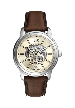 Fossil Herrenuhr mit Edelstahlgehäuse, beigem Zifferblatt mit sichtbaren Zahnrädern, schwarzen Markierungen und braunem Lederarmband.