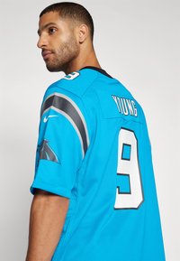 Carolina Panthers mez élénk kék színben, fekete és szürke kiegészítőkkel, nagy 9-es számmal és "YOUNG" névvel a hátsó oldalon. Poliészter anyag.
